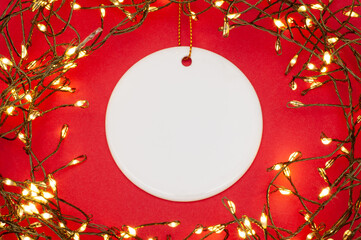 Round ceramic ornament framed by glowing Christmas string lights, flat lay festive holiday decor on...