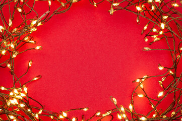 Christmas string lights glowing on red background, festive holiday garland decoration, top view...