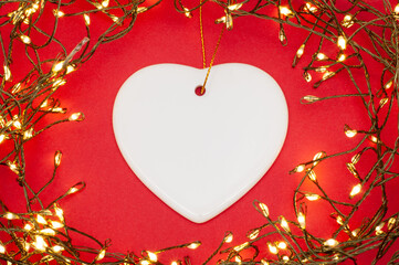 Heart ceramic ornament framed by glowing Christmas string lights, flat lay festive holiday decor on...