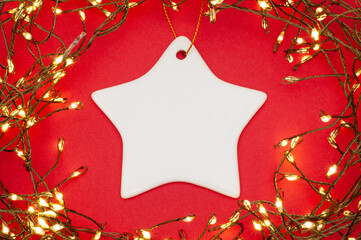 Star ceramic ornament framed by glowing Christmas string lights, flat lay festive holiday decor on...