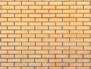 Yellow, beige brick wall texture with cement straight seam lines. New rectangular bricks. Background closeup.