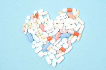 Pills arranged in a heart shape, flat lay top view on blue background, healthcare, medication, and...