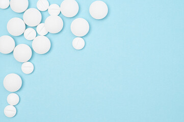 White round pills flat lay, top view on blue background with copy space, healthcare, medication,...