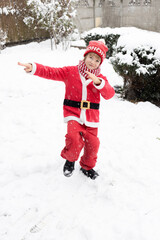 cheerful boy in red Santa suit happily dancing on snow. snowy weather, cold winter. Santa's helper....