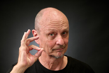 Closeup portrait of a elderly man in studio doying the sign for perfect