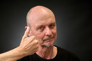 Closeup portrait of a elderly man in studio with thumbs up