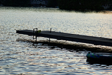 Wooden pier stretches into calm lake at dusk, reflecting last light of day across serene water....