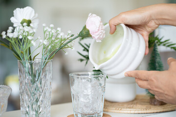 hand of woman holding a glass of iced matcha latte on table at cafe.