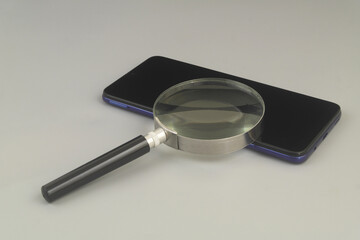 Checking and reviewing cellphones and apps concept. Smartphone under magnifying glass