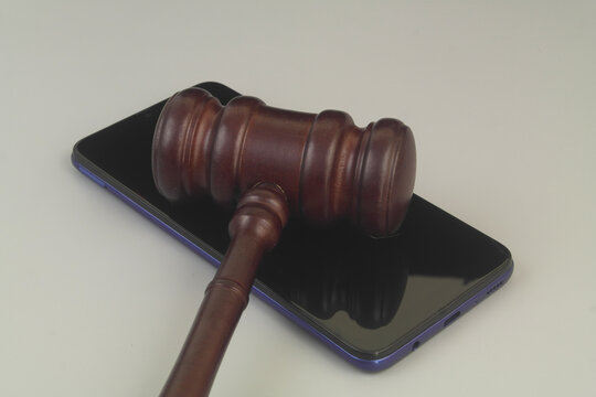 Smartphone and wooden judge gavel on grey background - Powered by Adobe