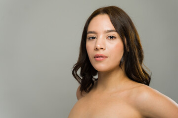 Fototapeta premium Beautiful woman showing glowing skin after skincare treatment in studio