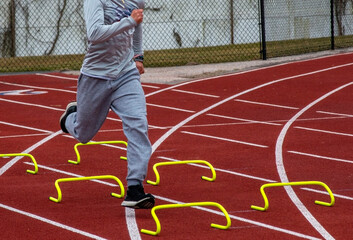 Athlete Training Over MiniHurdles on Outdoor Track in Springtime