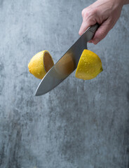 Fresh lemon halves cut in mid air with a sharp knife, isolated on a neutral background with copy...