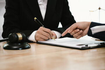 Two businessmen shake hands in an office, symbolizing agreement, partnership, and legal settlement....