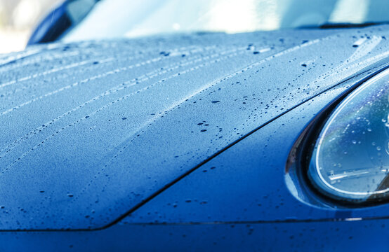 Fototapeta Close-up of a Blue Car Hood Reflecting Raindrops on PPF Car Paint Protection Film