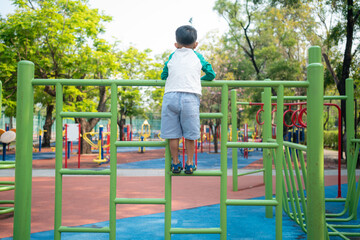 Happy asian boy climbing in outdoor playground public park