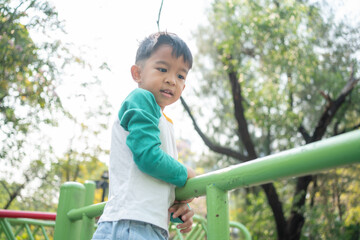 Happy asian boy climbing in outdoor playground public park
