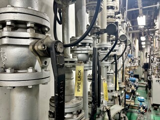 a complex network of industrial pipes, valves, and gauges. The image highlights the intricate machinery and heavy-duty equipment of a factory or processing plant, conveying an organized yet complex 