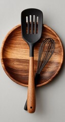 Wooden plate with black spatula and whisk