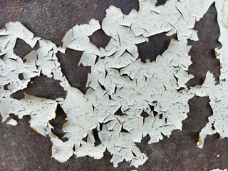 Peeling white paint on rusty metal surface, close-up of weathered texture, grunge background.
