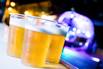 Plastic cups overflowing with refreshing beer at a lively night event