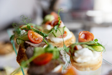 An assortment of elegant canapes with various meat and vegetable toppings on a glass tray