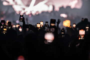 Crowd holding smartphones recording live music concert