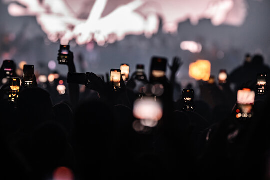 Crowd holding smartphones recording live music concert