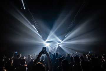 Crowd enjoying live music concert with bright stage lights illuminating dark arena © Zoran Jesic