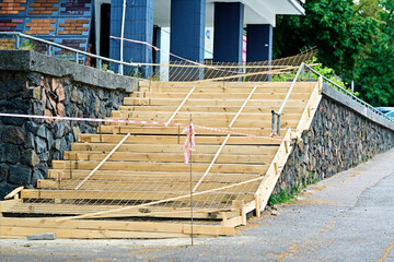 Wooden staircase under construction with unfinished framework, safety tape, and barriers, urban...