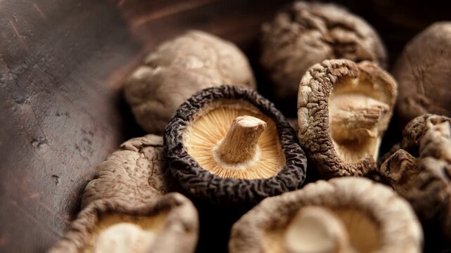 Dried edible shiitake mushrooms in a rustic wooden bowl. Rotation
