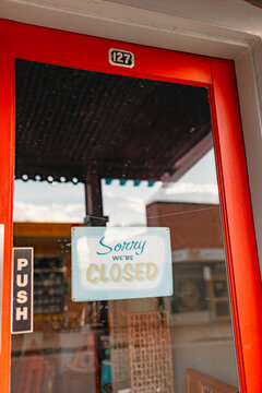 Sorry We're Closed sign on front door of small business, vertical image