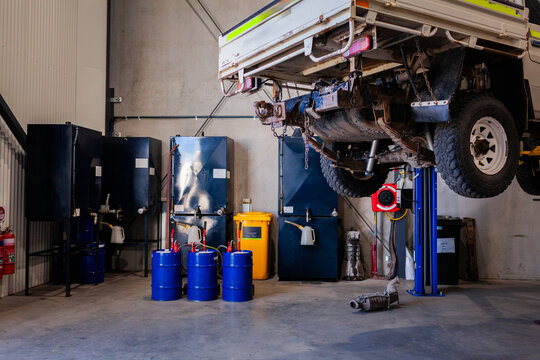 Mining fleet vehicle hanging on hydraulic lift inside workshop