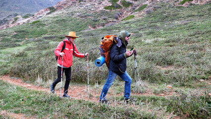 Two wanderers are walking along the path towards adventure. A gay couple with backpacks and...