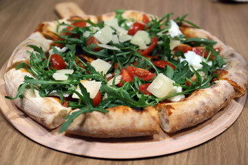 pizza artesanal italiana recién horneada con todos sus ingredientes, tomate, queso y rúcula