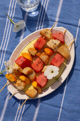 Grilled chicken and fruit skewers on plate with copy space top view