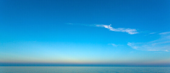 Calm ocean reflecting vibrant blue sky at sunset with cirrus clouds