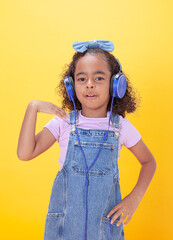 Cheerful, smiling Hispanic school-age girl with hearing aids making hand gestures,  on a yellow background.