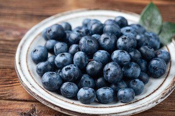 Blueberries on a plate. wooden table background. summer berry harvest