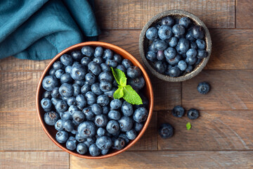 Fresh blueberries in bowl on a wooden table background, top view