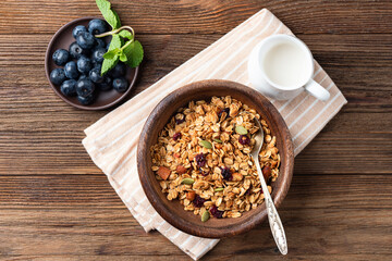 Homemade granola with dried cranberries and pumpkin seeds in wooden bowl, top view. Healthy food