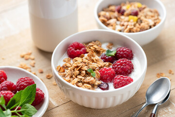 Granola bowl with yogurt and raspberries on wooden table background, closeup view, healthy diet meal
