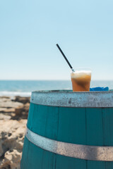 Iced drink on a blue barrel by the seaside in Italy under the summer sky