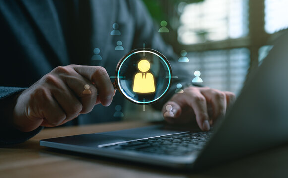 Businessman using magnifying glass to find candidate icon on digital interface, representing recruitment, human resource search, talent acquisition, job matching and employee selection process.