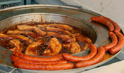 Fried greasy meat sausages on metal plate sold on market