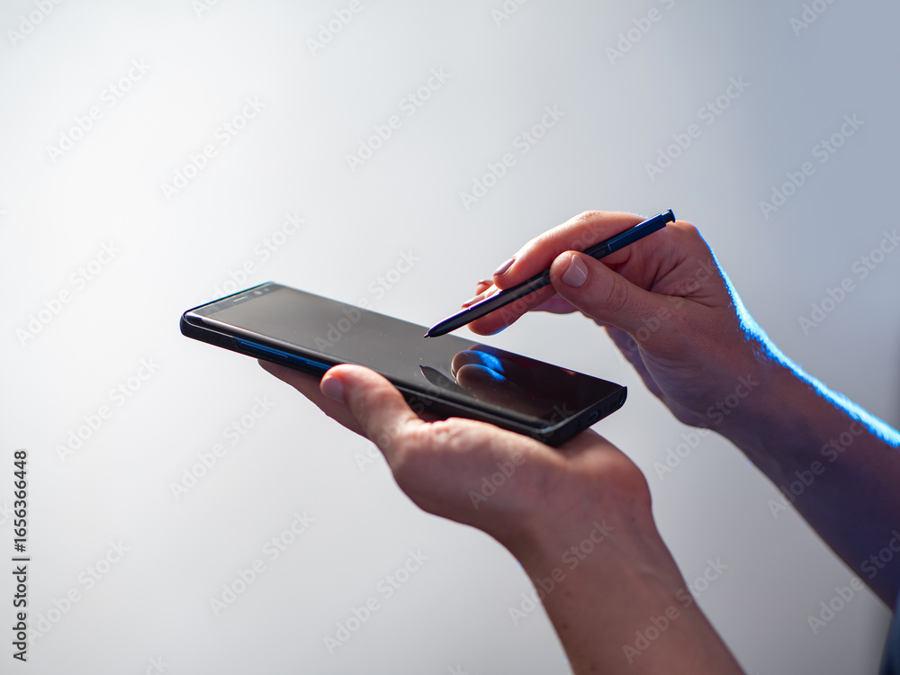 Aufkleber smartphone with stylus in human hands. touchscreen phone. hands with smartphone on light background.