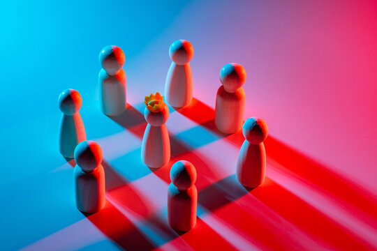 Team around leader. Miniature wooden men and king. Team listens to leader concept. Metaphor leadership in business. Figurines of company employees in blue and red. Leader inspires subordinates
