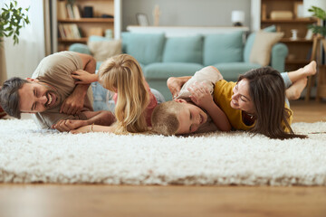 Playful parents having fun while tickling their small kids on floor in the living room