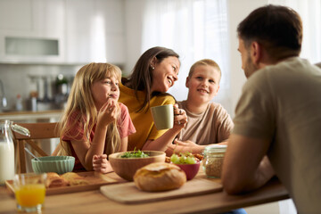 Happy family enjoying while having breakfast in dining room.