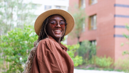 Young woman resting and relaxing while walking on city street in new eco-friendly residential...
